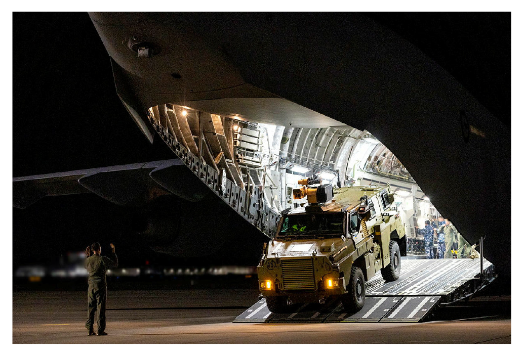 This is a photograph showing a Bushmaster protected mobility vehicle being unloaded from a C-17A Globemaster III aircraft in Europe