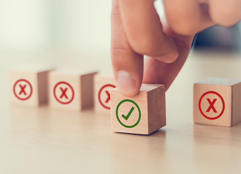 Person picking the cube with a green tick out of 4 red crossed cubes.