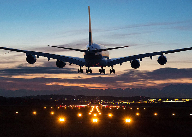 A passenger jet flies over the runway