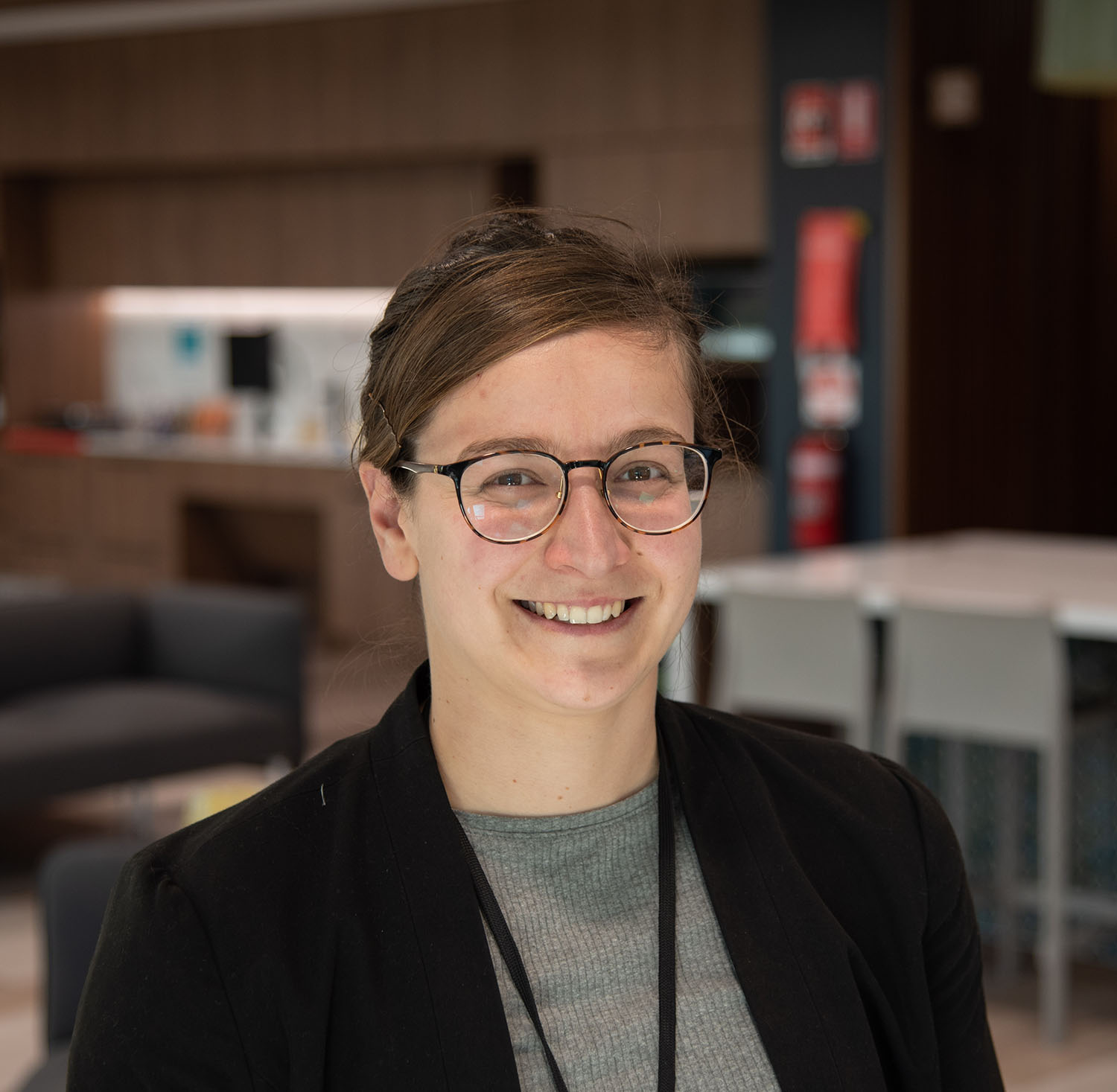 A woman with glasses smiles at the camera